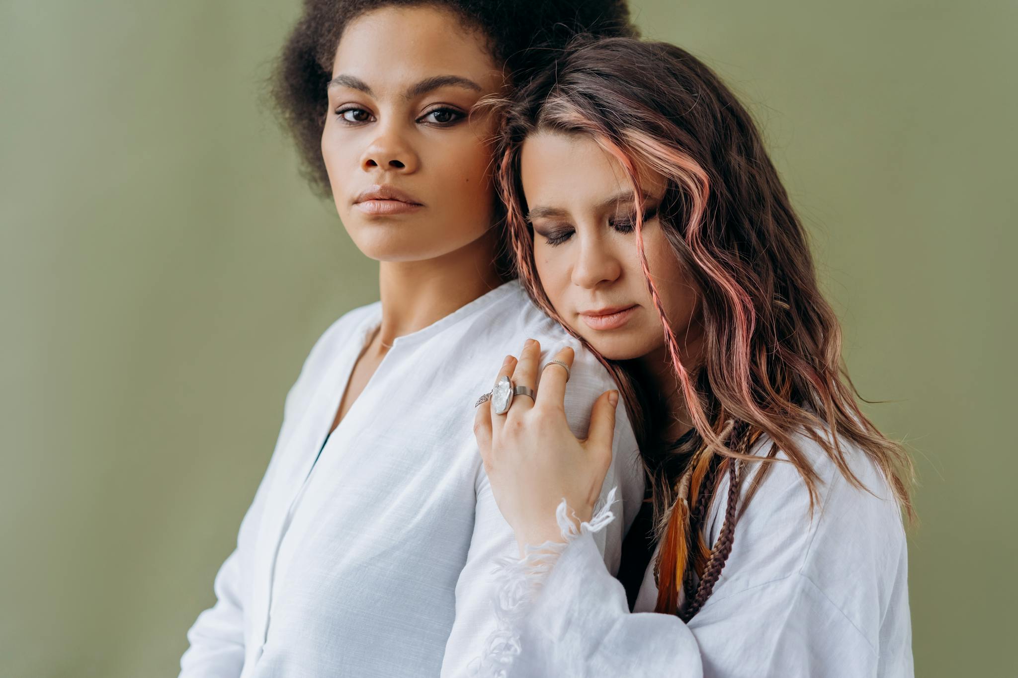 Intimate portrait of two women embracing, showcasing friendship and diversity against a neutral background.