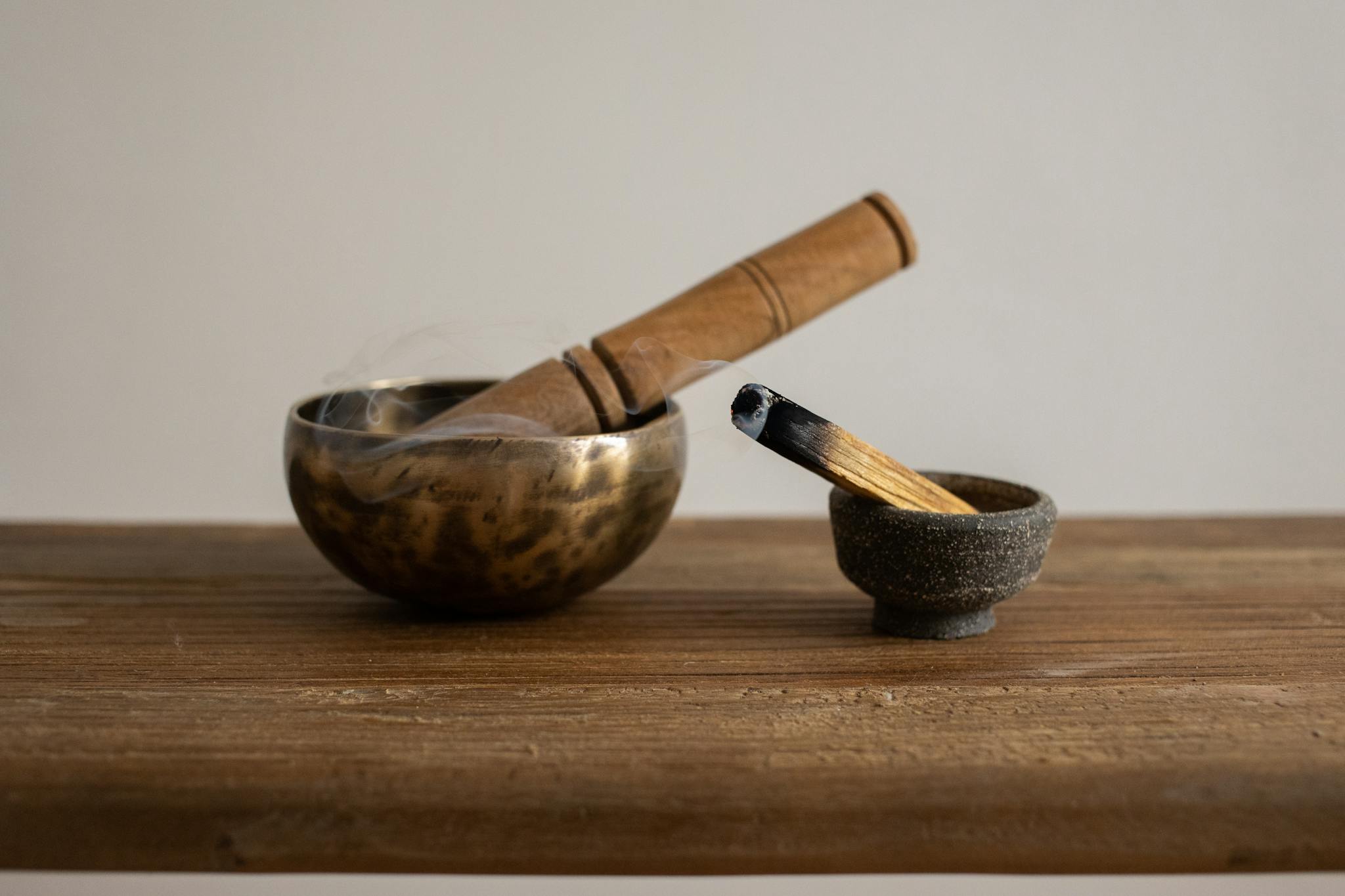 Singing bowl and burning incense on wooden table, ideal for relaxation and meditation